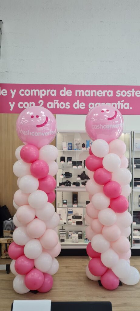 Globos decorativos rosas y blancos con caras sonrientes, ideales para fiestas y eventos, formando arcos llamativos para decorar celebraciones infantiles o temáticas.